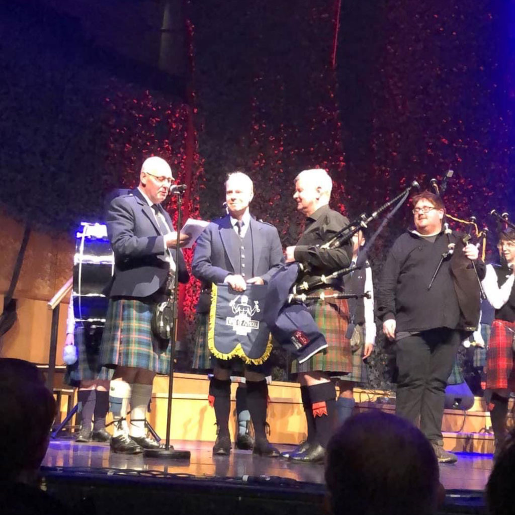Ian Duncan being presented with the pipe banner
